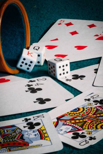 A vertical shot of poker dices, a cup, and cards on a green mat